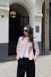a lady in a white top, a pink tweed coat and a pair of black pants